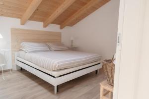 a bedroom with a white bed with a wooden ceiling at Casa ALMA in Colico
