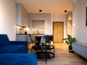a living room with a blue couch and a kitchen at Apartament Termalny in Uniejow