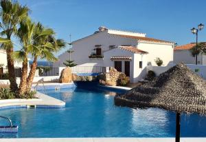- une piscine en face d'une maison avec des palmiers dans l'établissement Ker Sonrisa, à Nerja