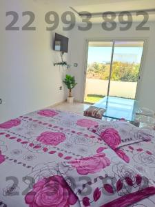 Un dormitorio con una cama con flores rosas. en S+2 pied dans l'eau kerkouane SOF 22993892 en Kerkouene