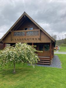 a large wooden cabin with a tree in front of it at Luxury 3 bedroom, 3 bathroom lodge with hot tub in Llanbedr