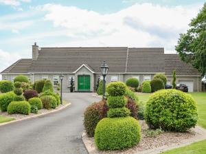 a house with a green door and some bushes at The Hideaway in Magherafelt