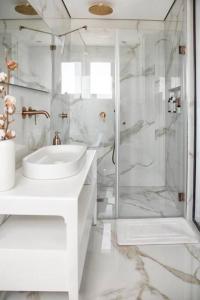 een witte badkamer met een wastafel en een douche bij A large and well-designed apartment with a stunning view in Or ‘Aqīvāh