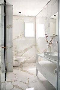 een witte badkamer met een wastafel en een toilet bij A large and well-designed apartment with a stunning view in Or ‘Aqīvāh
