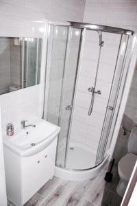a white bathroom with a shower and a sink at Rumiankowa Polana in Sarbinowo