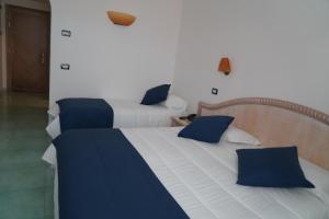 two beds with blue and white sheets in a room at Hotel Albatros in Ischia