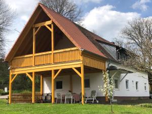 ein Haus mit einem Gameradach mit Tischen und Stühlen in der Unterkunft Ferienwohnung am Rohrbacherhof Sabine Rück in Barackenhöfe