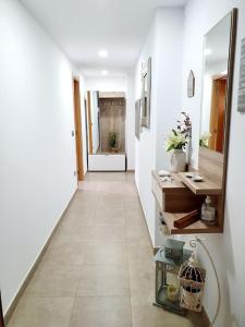 a hallway with white walls and a tile floor with a mirror at Benicassim SunHouse - Hermoso ático en el Pueblo - Aire acondicionado y BBQ area in Benicàssim