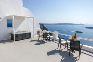 a balcony with a table and chairs and the ocean at Asma Suites in Fira