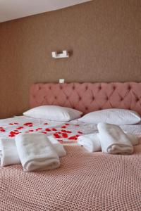 a bed with white towels and red flowers on it at M&W Hotel Wronowski in Łomża