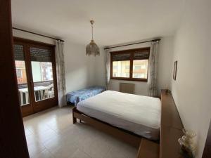 a bedroom with a bed and two windows at Appartamento Dona Comano Terme in Ponte Arche