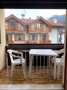 a white table and chairs on a balcony with a building at Appartamento Dona Comano Terme in Ponte Arche