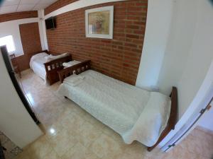 1 dormitorio con 2 camas y pared de ladrillo en Las Catalinas cabañas en San Fernando del Valle de Catamarca
