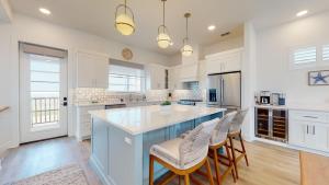 a kitchen with white cabinets and a blue island with bar stools at Dorado Dunes #D Newly Built, Gorgeous Beach Home, Private Pool, Golf Cart Entire Stay in Port Aransas