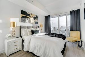 a white bedroom with a large bed and a chair at Waterfront Luxury Condo in Toronto