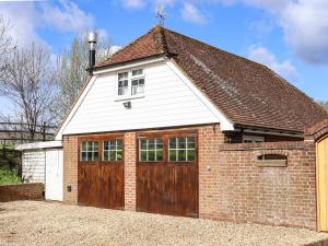 a red brick garage with a large wooden door at Orchard Retreat in Paddock Wood