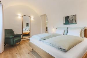 ein Schlafzimmer mit einem Bett, einem Stuhl und einem Spiegel in der Unterkunft Pizzol-hof in Appiano sulla Strada del Vino