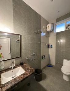 a bathroom with a sink and a toilet and a mirror at Kaashi Flora (Full Villa - 5 Bedrooms) in Varanasi