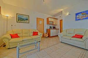 a living room with two couches and a kitchen at Apartmani Vila Nela in Postira