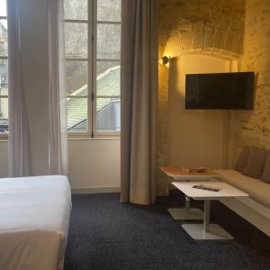 ein Hotelzimmer mit einem Bett, einem Sofa und einem TV in der Unterkunft Le Roscanvec in Vannes