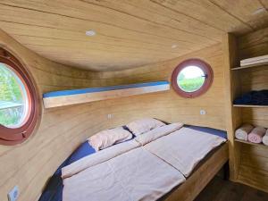 Cama pequeña en habitación pequeña con 2 ventanas en Glamping Rajska vas en Šentjur