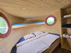 a small bed in a small room with two windows at Glamping Rajska vas in Šentjur