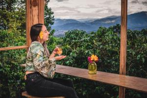 una mujer sentada en un banco sosteniendo una bebida en Tierra Activa Alojamiento Eco Rural finca orgánica y agroturística, en San Agustín