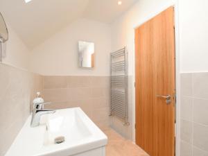 a bathroom with a white sink and a wooden door at Waterston Cottage in Wareham +34 photos