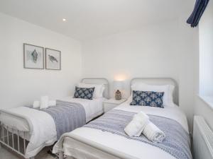 two twin beds in a room with white walls at Waterston Cottage in Wareham