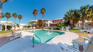 una piscina con sillas y palmeras en FD115 Spacious Home in Royal Sands, Shared Pool & Hot Tub, Golf Cart Included, Beach Boardwalk en Port Aransas
