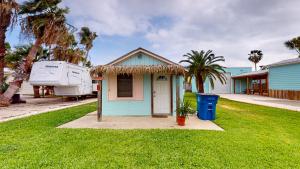 a small blue house in a yard with palm trees at NS731 Coastal Cottage, In Town Near Shops, Restaurants and Nightlife in Port Aransas