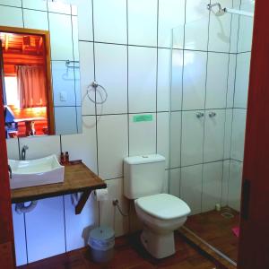 y baño con aseo, lavabo y espejo. en Pousada Cabanas Xokleng, en Urubici