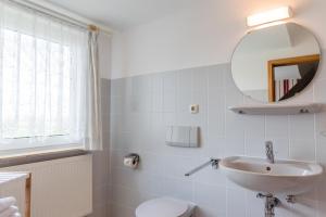 a white bathroom with a sink and a mirror at Straendhus Bed&Breakfast in Hasselberg