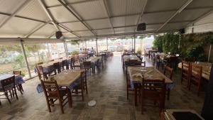 an empty restaurant with tables and chairs and people in the background at VANGJELIS HOTEL in Himare