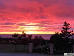 una puesta de sol sobre el océano con un cielo rojo en La Villa Céleste, en Sainte-Luce-sur-Mer