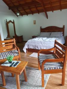 a bedroom with a bed and two chairs and a table at Recanto das Tirivas in Monte Verde