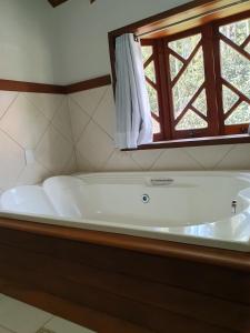 uma banheira num quarto com uma janela em Recanto das Tirivas em Monte Verde