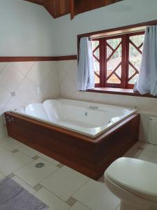uma banheira na casa de banho com uma janela em Recanto das Tirivas em Monte Verde