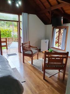 uma sala de estar com duas cadeiras e uma mesa em Recanto das Tirivas em Monte Verde