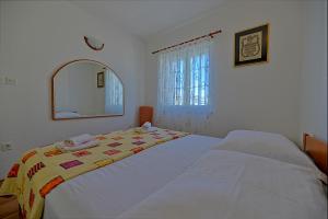 a bed in a bedroom with a mirror and a bedspread at Apartmani Vila Nela in Postira
