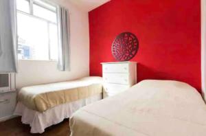 a bedroom with two beds and a red wall at MARCOLINI - Cobertura Vista Mar na Praia de Copacabana in Rio de Janeiro