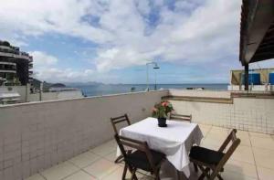 una mesa y sillas en un balcón con vistas al océano en MARCOLINI - Cobertura Vista Mar na Praia de Copacabana en Río de Janeiro