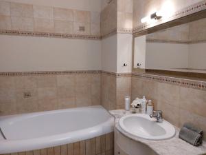 een badkamer met een wastafel, een bad en een spiegel bij Apartament Radosna in Gdynia