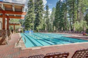 a large swimming pool with chairs in front of trees at Flurry by AvantStay Tahoe Donner Home w Access to Northstar Resort Community in Kingswood Estates