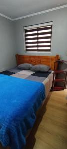 um quarto com uma cama com um cobertor azul e uma janela em EL ROBLE 2.0 CHILLAN em Chillán
