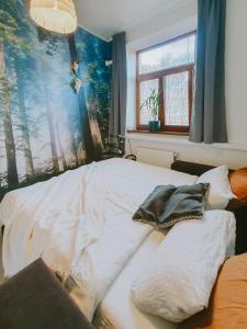 an unmade bed in a bedroom with a painting on the wall at Priestranný apartmán v centre in Košice