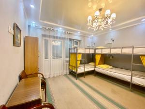 Pokój z 2 łóżkami piętrowymi, stołem i żyrandolem w obiekcie Downtown Homestay w mieście Biszkek