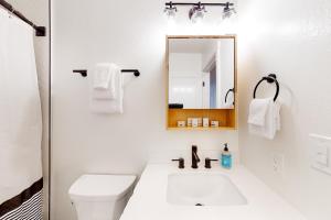 La salle de bains blanche est pourvue d'un lavabo et d'un miroir. dans l'établissement Piney Point, à Arnold