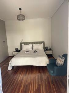 sypialnia z dużym łóżkiem i niebieskim krzesłem w obiekcie Spacious modern 2 bedroom apartment south coast of Athens w Atenach