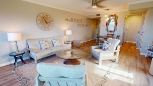 a living room with a couch and chairs and a clock at IR145 2nd Floor Condo, Ocean View, 1 Bedroom, Shared Pools, Boardwalks in Port Aransas